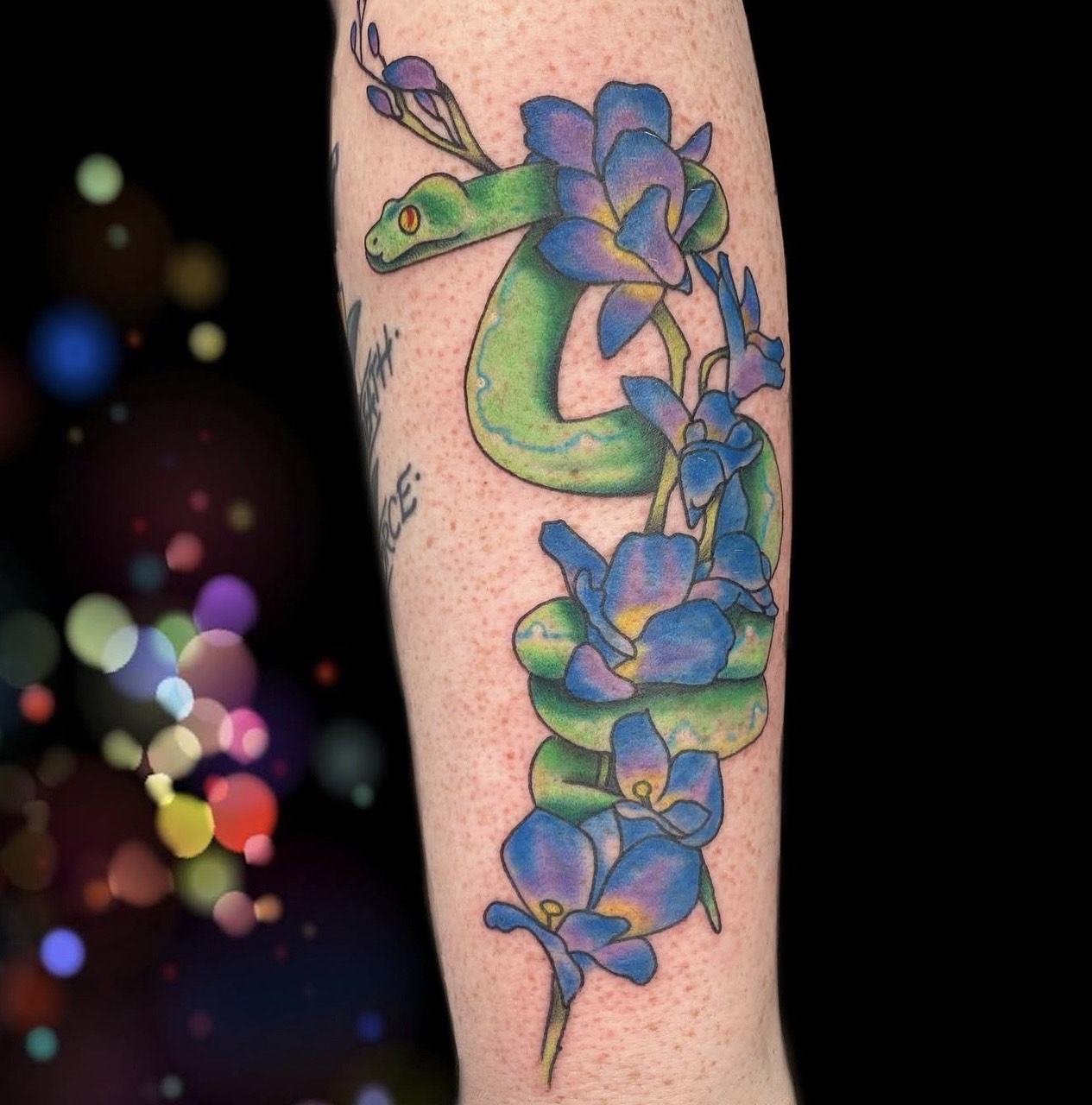 Green snake with blue flowers color tattoo